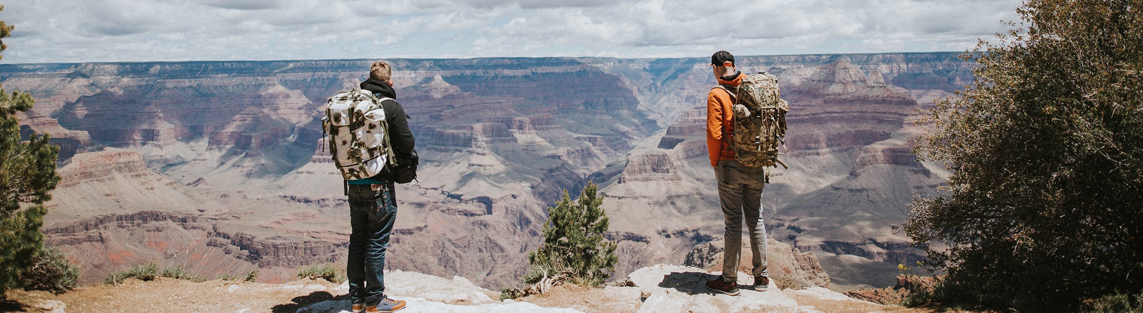 Two backpackers overlooking the Grand Canyon on an adventure tour.