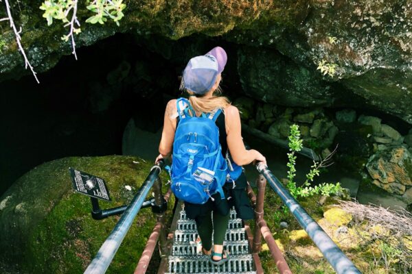 Woman hikes into a cave at Lava Beds National Park on a group camping adventure tour