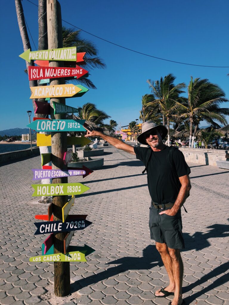 Man points in the direction of a sign pointing in all directions.