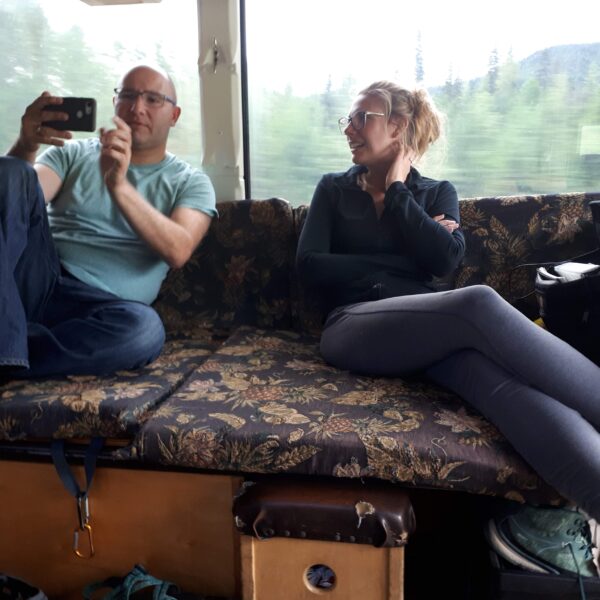 Two people ride on the adventure bus on a 3-day San Francisco to Seattle camping trip.