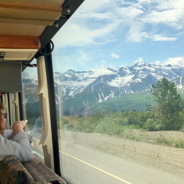 A woman points to the Alaska Range on a Green Tortoise Adventure Bus