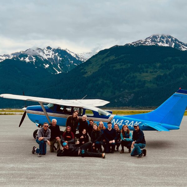 Green Tortoise passengers pose in front of a small plane in Haines, Alaska