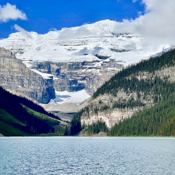 A mountain covered in glaciers sits above Lake Louise in Banff National Park.
