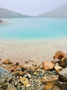 An emerald lake brings color to a foggy, colorless day hike