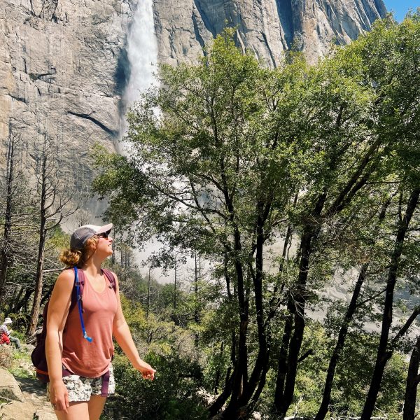 A woman looks up at Upper Yosemite Falls in Yosemite National Park