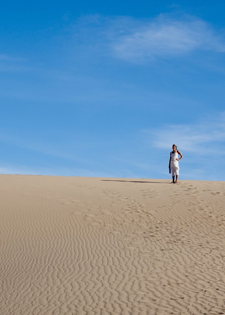 A woman stands in the sand on a desert camping adventure.
